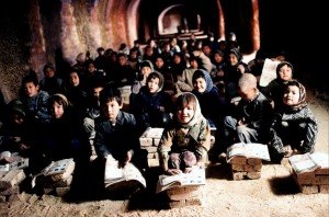 Fotograma donde se ve la clase con todos los niños sentados atendiendo a la profesora.