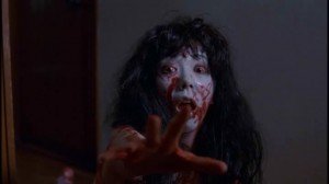 Fotograma de la secuencia de Kayako Saeki bajando tumbada las escaleras en La maldición.