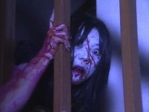 Kayako se arrastra hasta Kobayashi por las escaleras.