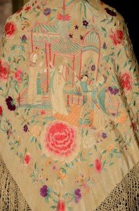 Mantón en el que transcurre una escena con dioses, una pagoda, relacionada con los dioses, y un tridente, símbolo de la trinidad taoísta.