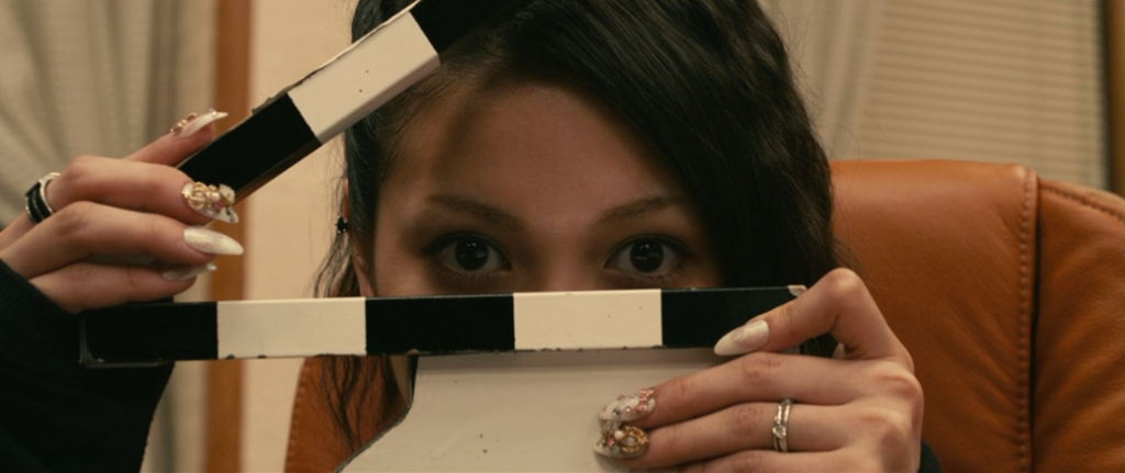 Mitsuko mira a cámara mientras juega con una claqueta.