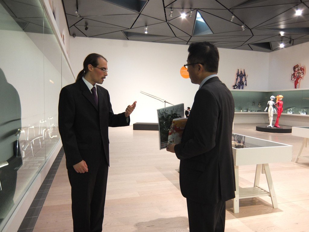 El embajador de Japón, Koshikawa Kazuhiko, con un ejemplar de Ecos de Asia, en una visita a la exposición guiada por M. S. 