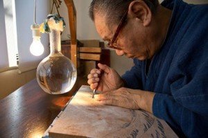 Artesano trabajando una plancha de grabado.